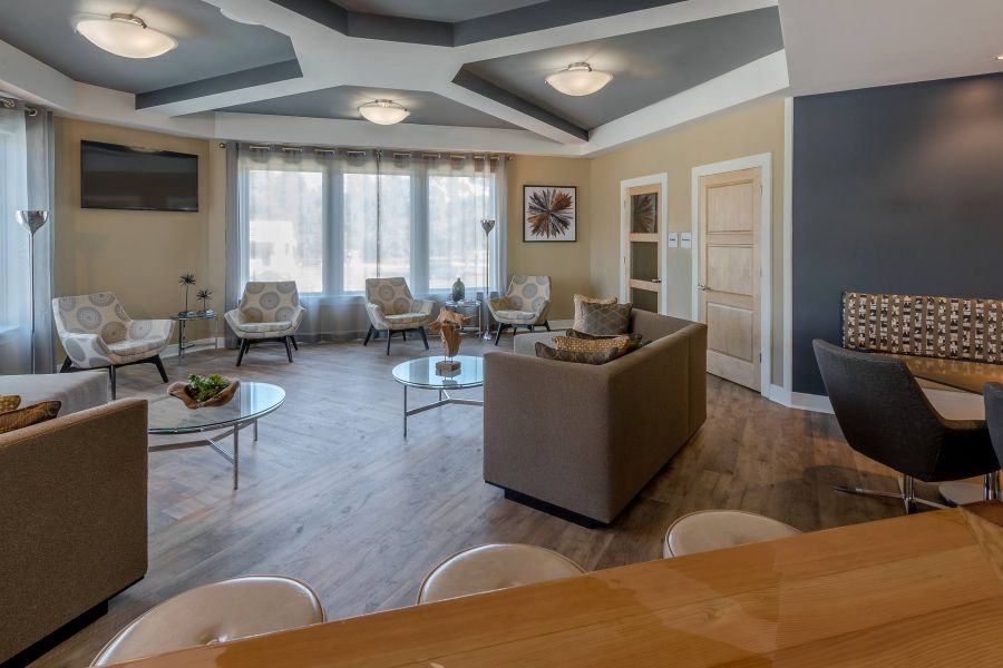 The Amber at Greenbrier Modern lounge with sofas, armchairs, coffee tables, and large windows letting in natural light.