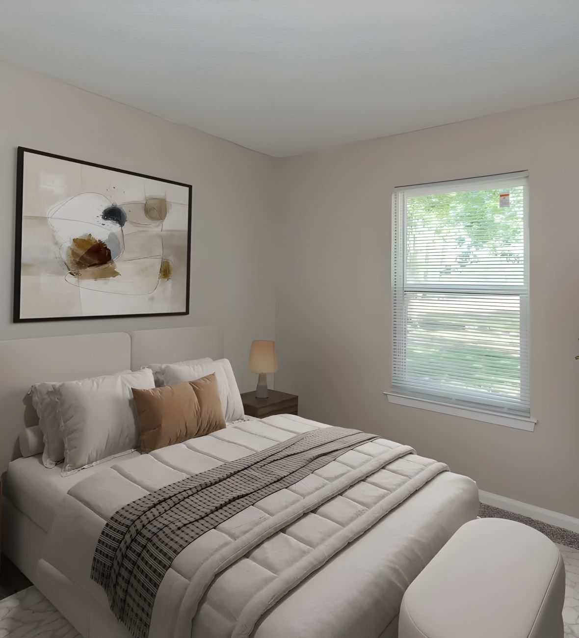 The Amber at Greenbrier A modern bedroom with a made bed, abstract art, a nightstand, lamp, and a window with blinds.