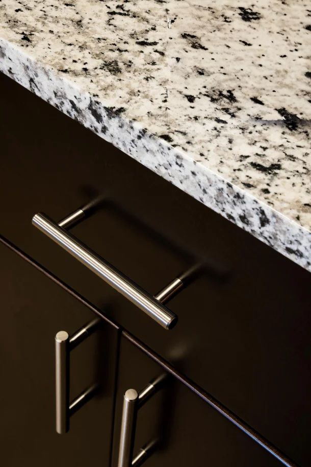 The Amber at Greenbrier Close-up of a speckled granite countertop above dark cabinets with silver handles.