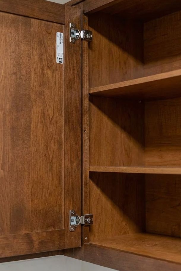 The Amber at Greenbrier Open wooden cabinet with adjustable shelves and visible metal hinges on the door.