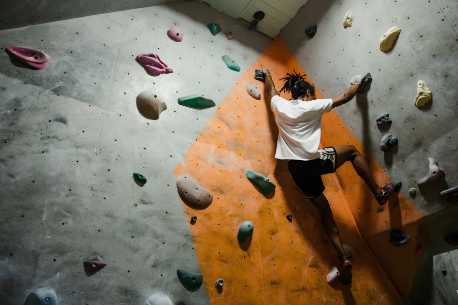 The Amber at Greenbrier A person climbs an indoor bouldering wall with colorful holds and an orange section.