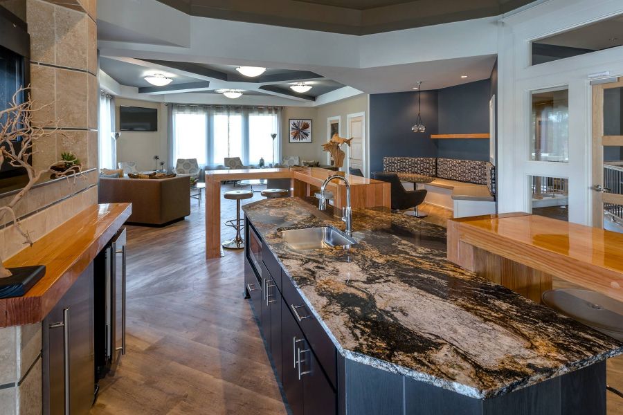 The Amber at Greenbrier Modern open kitchen with a marble island, wood accents, and seating area in a spacious living space.