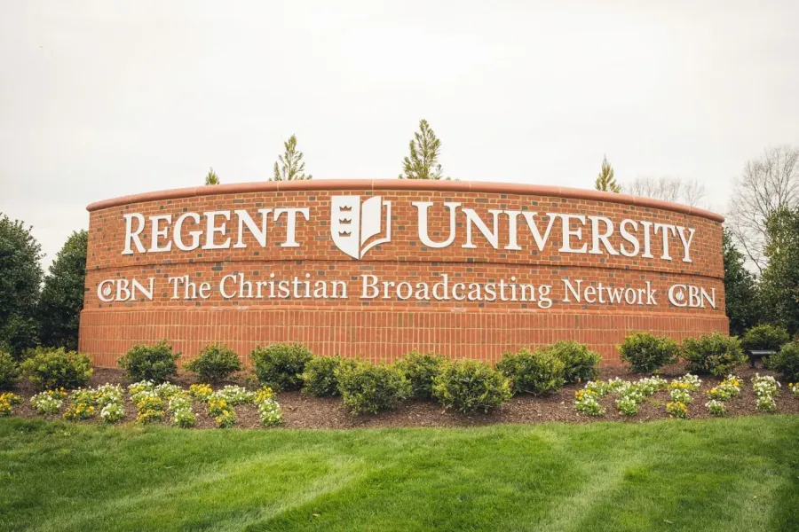 The Amber at Greenbrier A brick sign reads "Regent University CBN The Christian Broadcasting Network" with greenery in front.